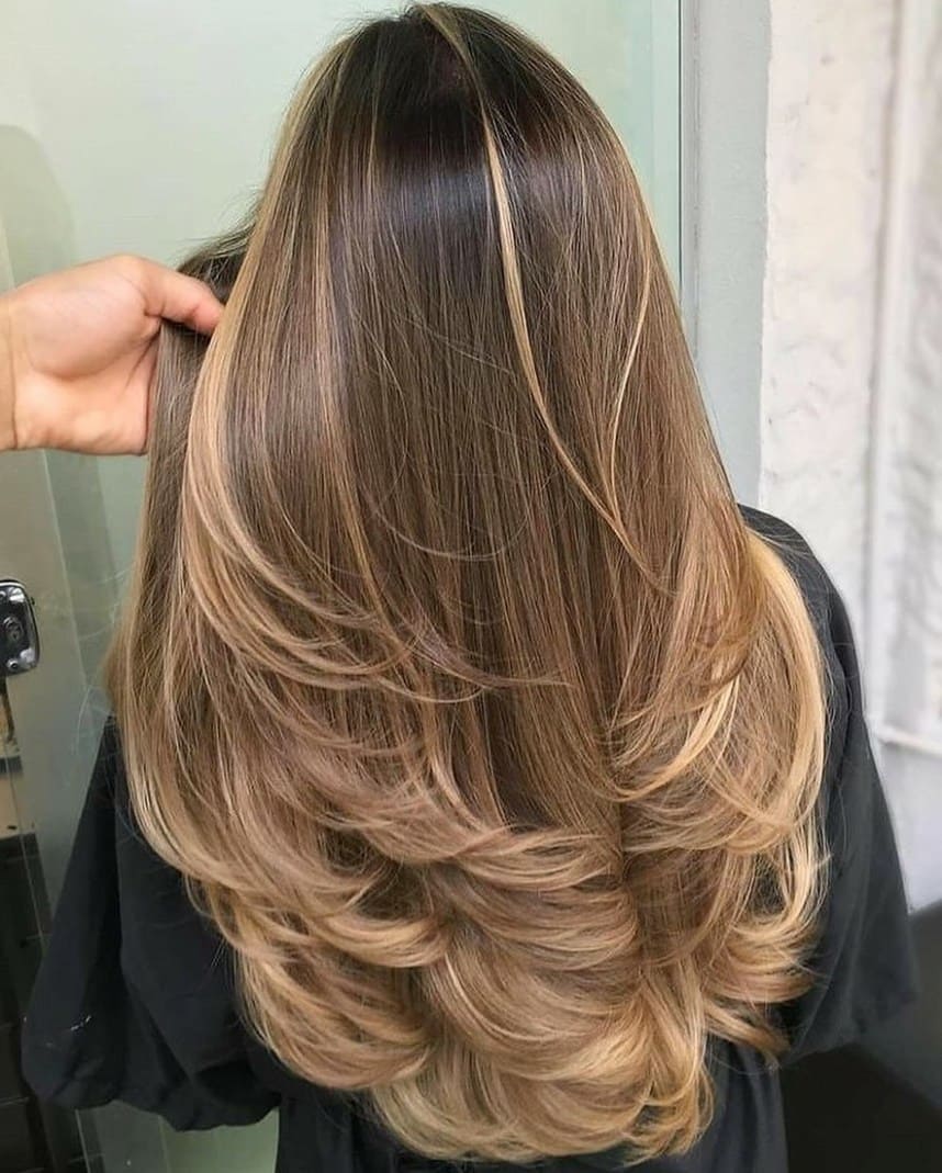 Corte degradado em cabelos longos com mechas loiras