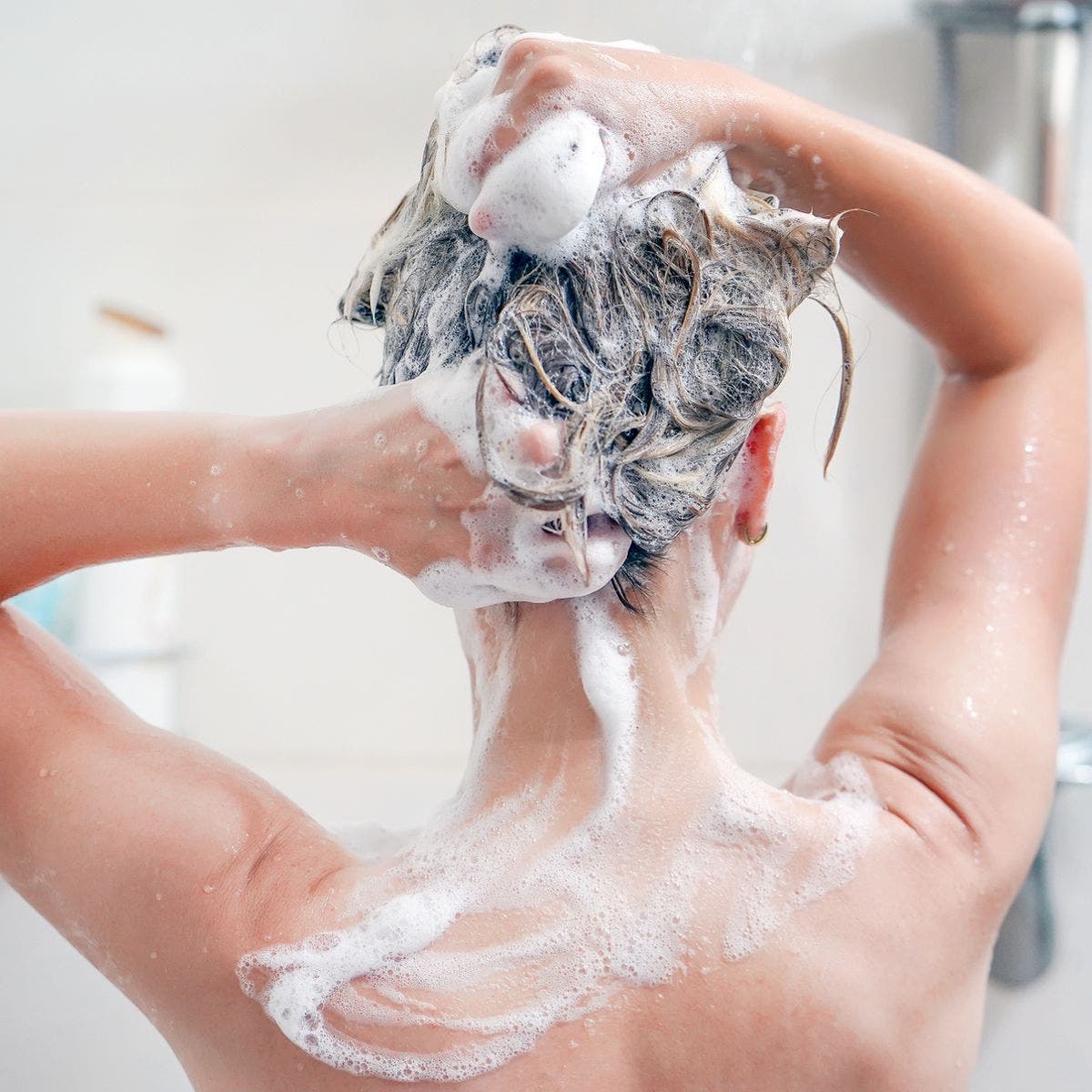 1 Rückansicht einer jungen Frau, die sich die Haare wäscht
