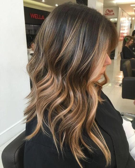 Cabelos longos com balayage loiro mel e pontas levemente onduladas