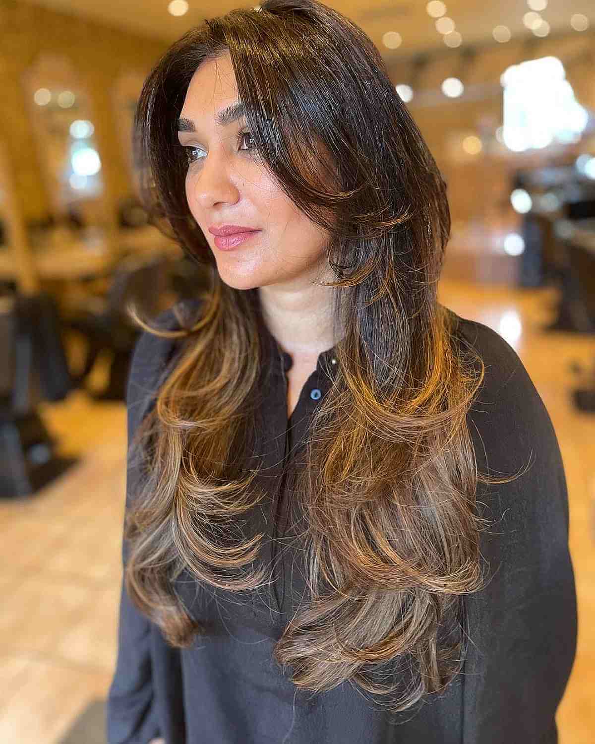 Cabelo castanho comprido com pontas onduladas e balayage caramelo