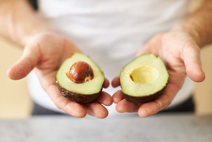 Aguacate cortado por la mitad con hueso