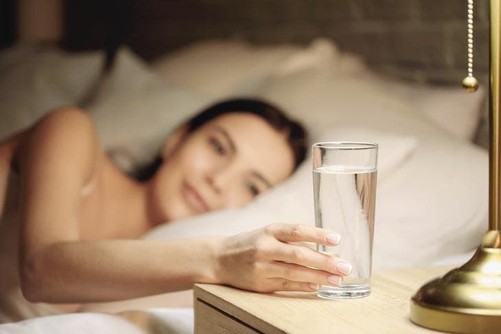 Drink a glass of water placed on the nightstand.
