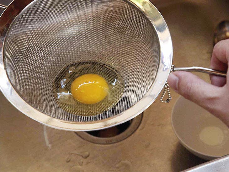 Crack an egg into a colander