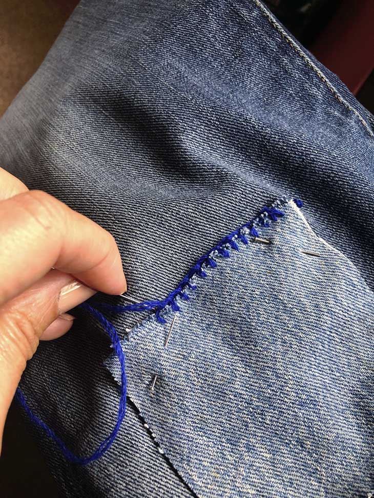 Sewing jeans with holes by hand.
