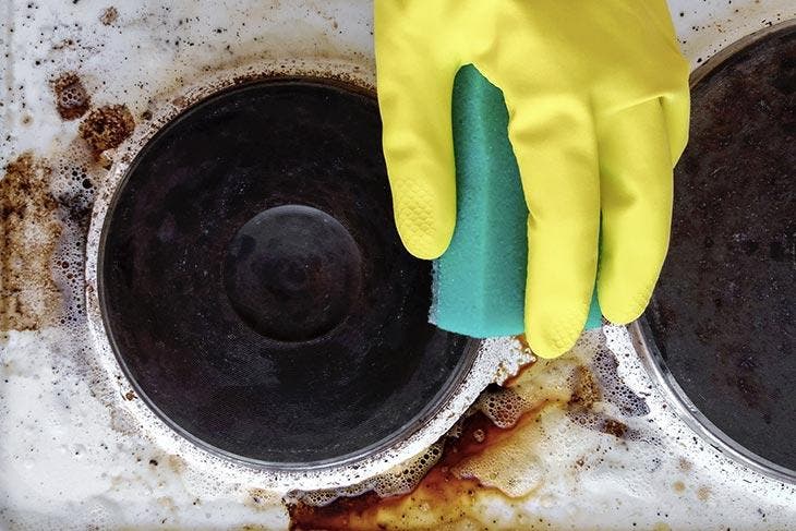 Esponja más líquido lavavajillas para limpiar la superficie de una placa de cocción