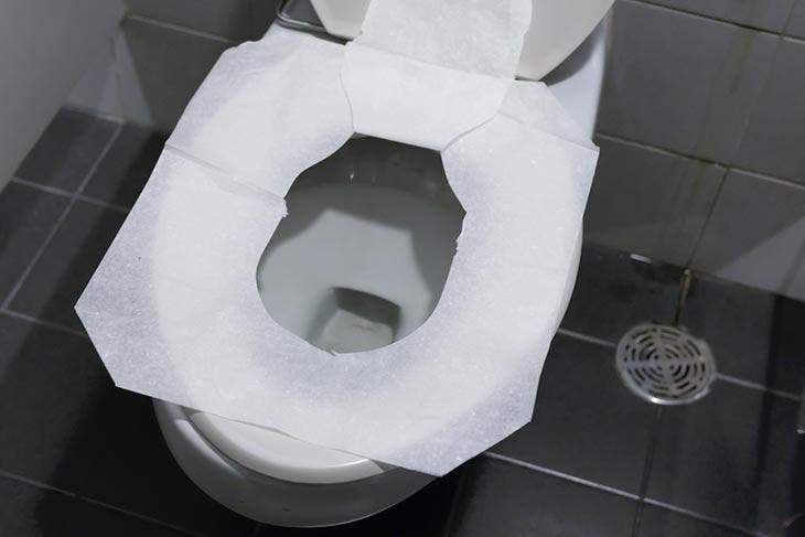Cover the toilet seat with paper.