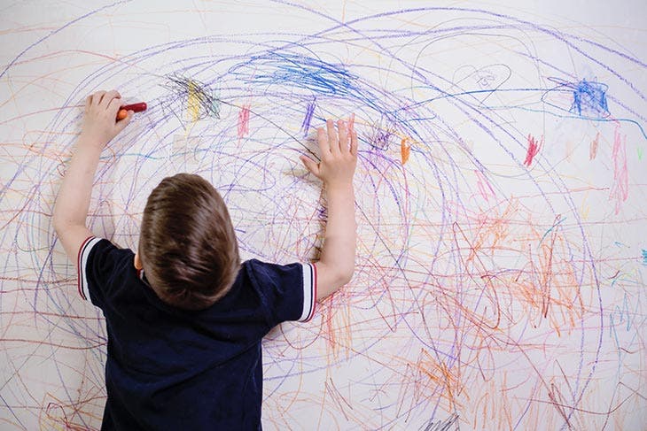 Niño garabateando en una pared