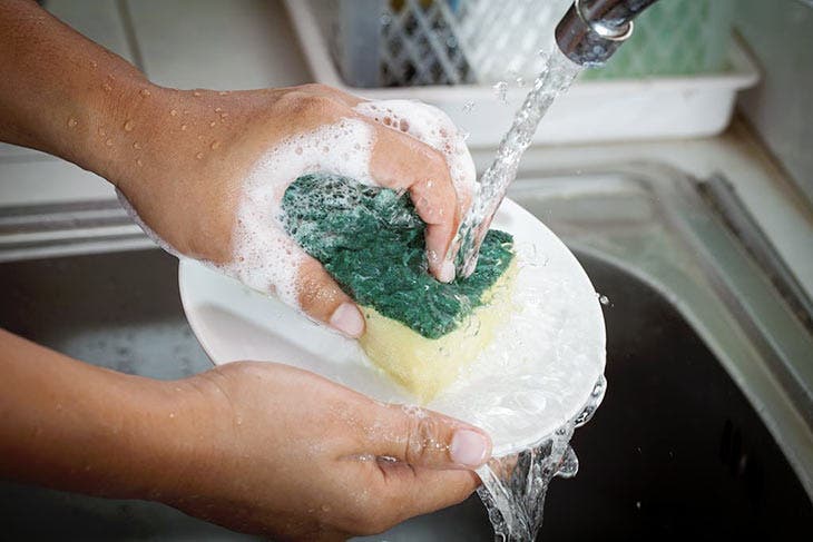 Lavar los platos con una esponja para platos.
