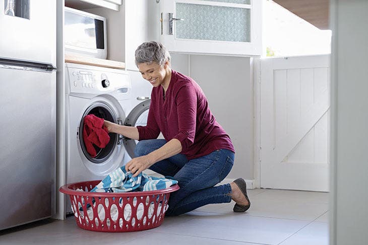 Femme mettant son linge dans la machine à laver