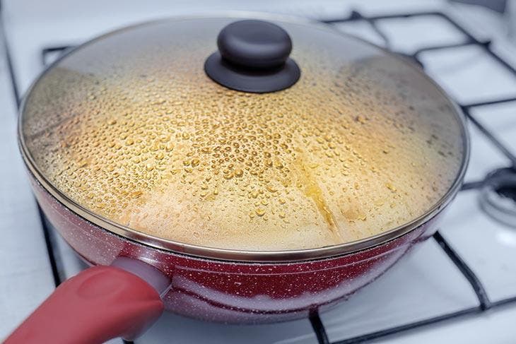 Gotas de agua debajo de la tapa de la sartén al cocinar