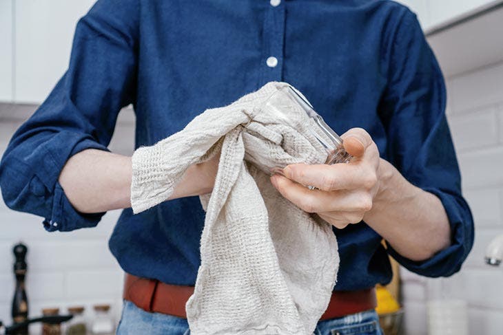 Hombre limpiando un vaso con una toalla de cocina