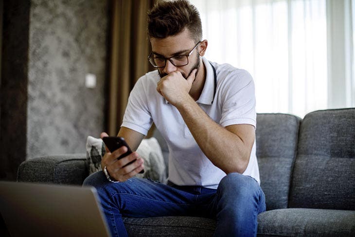 Joven sosteniendo su teléfono, luciendo preocupado