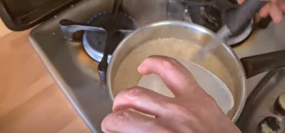 O cozinheiro derrama a mistura de amido de milho e leite na panela