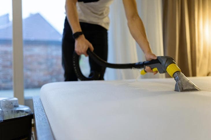 Vacuuming the surface of the mattress