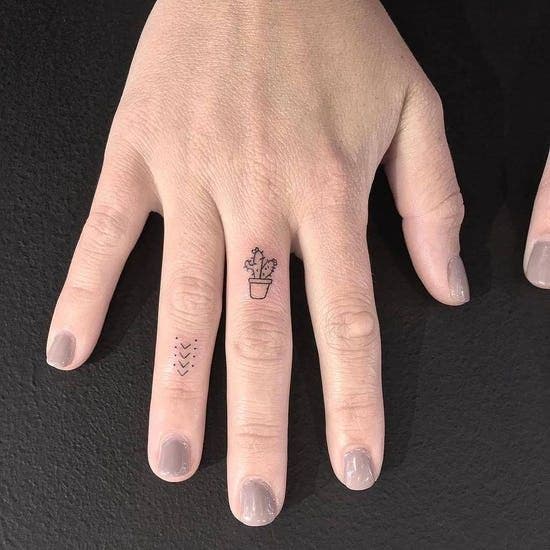 Petit cactus tatoué sur le doigt majeur Petit cactus tatoué sur le doigt majeur