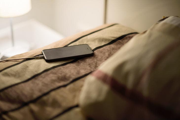 Aufladen des Smartphones auf dem Bett