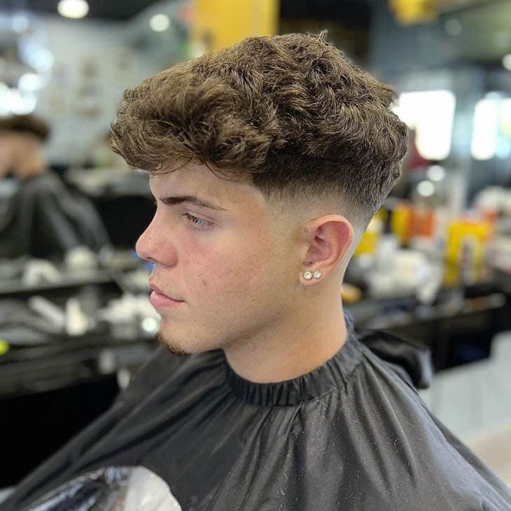 Taper fade bas avec cheveux bouclés et volume sur le dessus Taper fade bas avec cheveux bouclés et volume sur le dessus