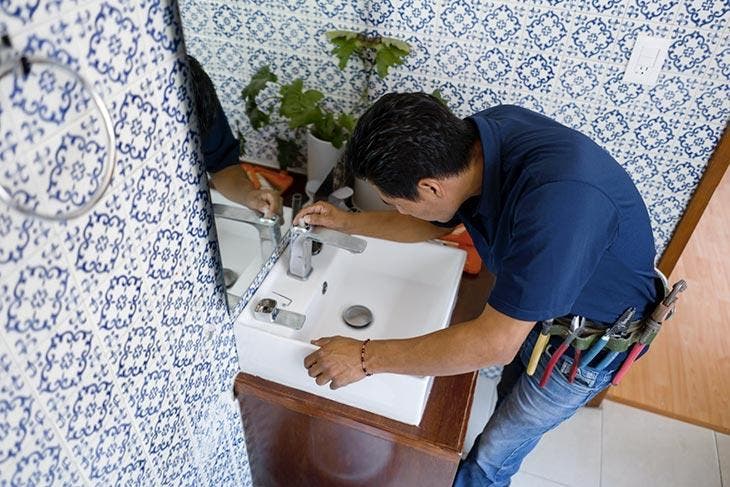 A plumber repairs the sink.
