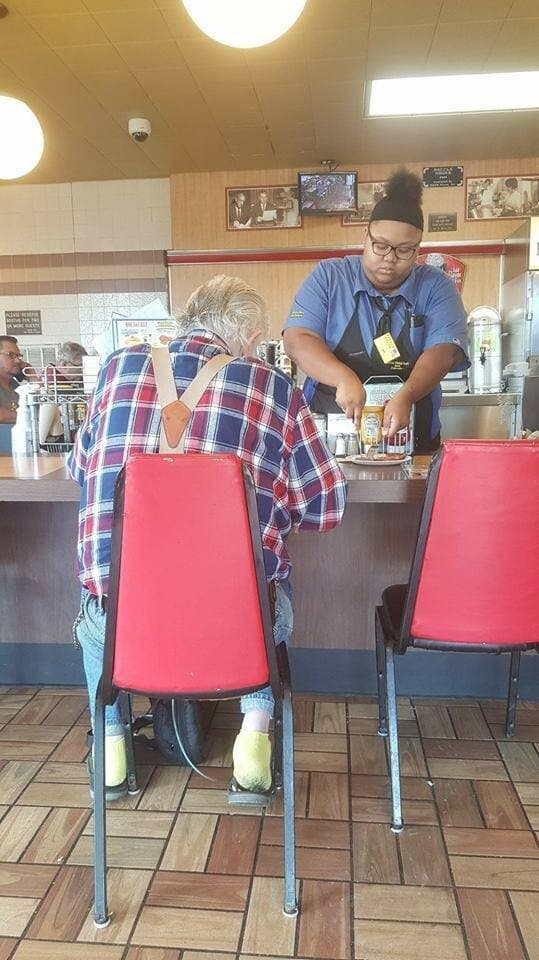 Une femme prend une photo en cachette, pour révéler ce que la serveuse fait de la nourriture du vieil homme