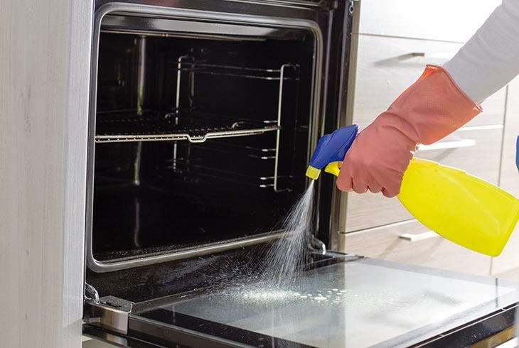 Pulverizar limpiador sobre el cristal de la puerta del horno