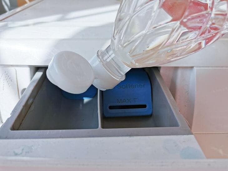 Pour white vinegar into the washing machine drawer.