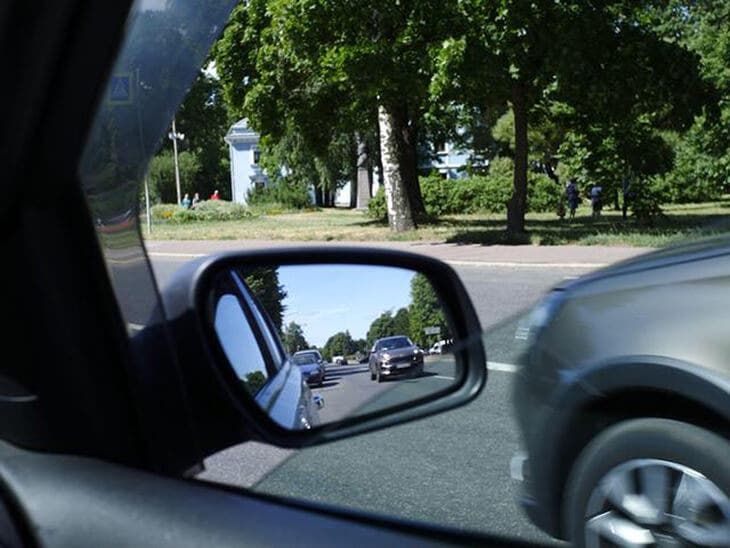 Vedere sullo specchietto retrovisore prima di aprire la portiera dell'auto