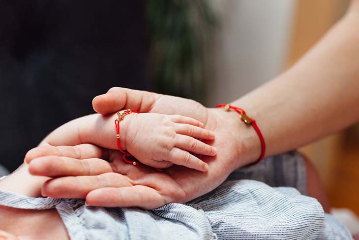 Un bébé et sa maman portant un bracelet rouge 